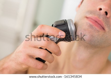 Extreme Close Up Of A Handsome Young Man Shaving With Electric Razor