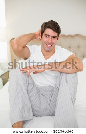 Portrait of a smiling young man sitting in bed at home