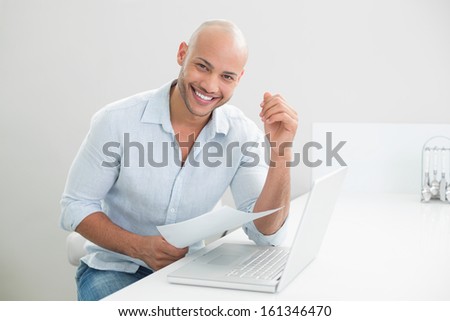 Portrait of a smiling casual young man with laptop sitting at home