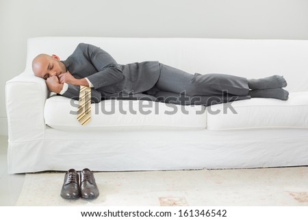 Full length of an elegant businessman sleeping on sofa at home