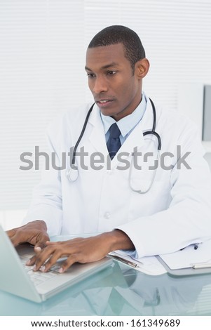Concentrated male doctor using laptop at medical office