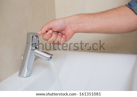 Extreme Close up of a plumber\'s hand opening a water tap at bathroom