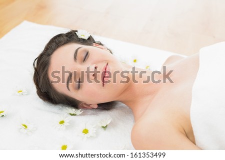 Close up of a beautiful young woman with eyes closed and flowers in beauty salon