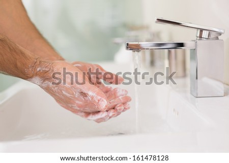 Close up of washing hands with soap under running water at bathroom sink