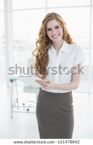 Portrait of a young elegant businesswoman writing notes in a bright office