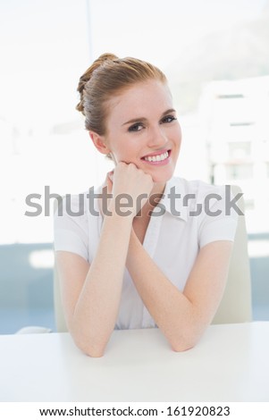 Portrait of a smiling businesswoman sitting at desk in a bright office