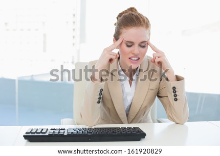 Young businesswoman suffering from headache at office desk