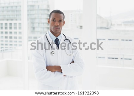 Portrait of a serious male doctor standing with arms crossed in a medical office
