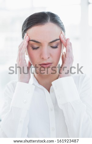 Close up of an elegant businesswoman suffering from headache in a bright office