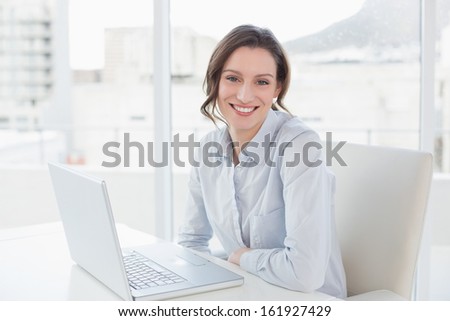 Portrait of a smiling young businesswoman with laptop in a bright office