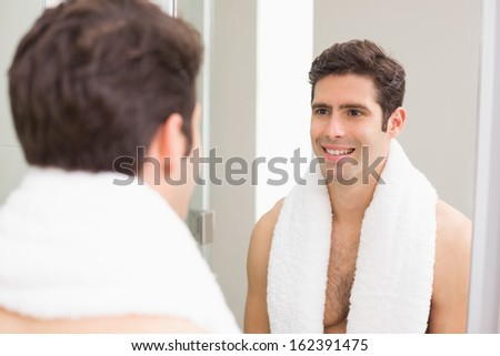 Rear view of a young man smiling at self in mirror in the bathroom