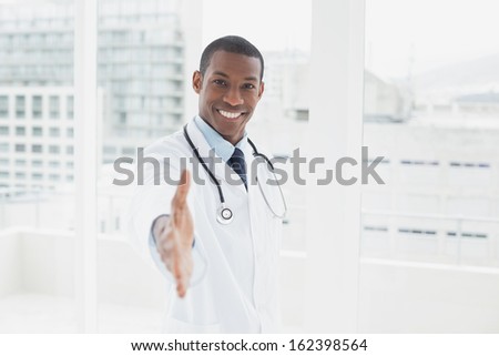 Portrait of a smiling male doctor offering a handshake in a medical office
