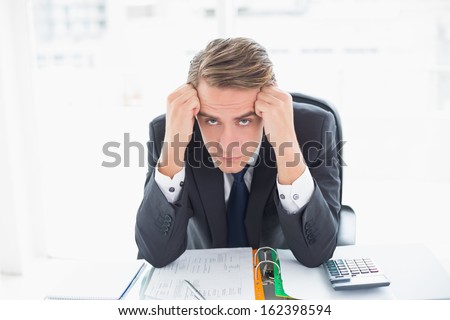 Portrait of a worried young businessman sitting with head in hands at office desk