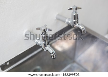 Close up of two taps and stainless steel kitchen sink