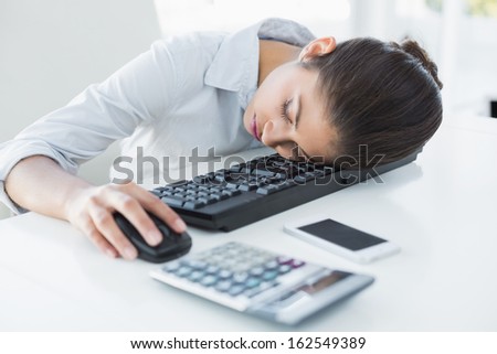 Young businesswoman resting head on keyboard in the office