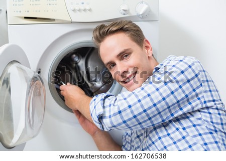 Portrait of a smiling technician repairing a washing machine