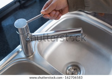 Extreme Close up of a plumber\'s hand opening a water tap at bathroom