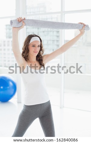 Fit young woman holding up towel in a bright fitness studio