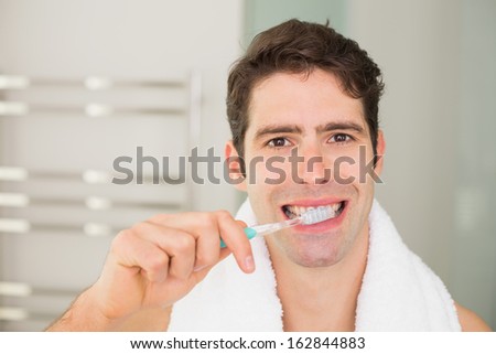 Close up portrait of a young man brushing teeth in the bathroom