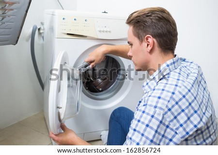Side view of a technician repairing a washing machine