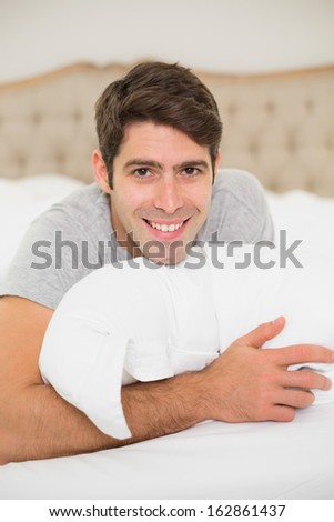 Close up portrait of a smiling young man resting in bed at home