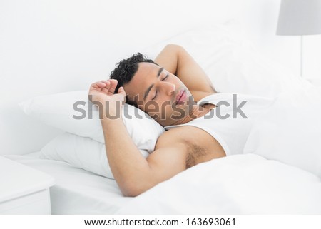 Side view of a young man sleeping in bed at home