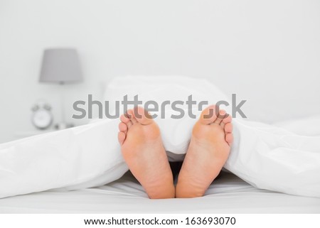 Close-up of bare feet in bed at home