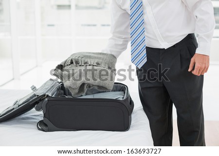 Mid section of a businessman unpacking luggage at a hotel bedroom