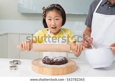 Shocked young girl with her father preparing cookies in the kitchen at home