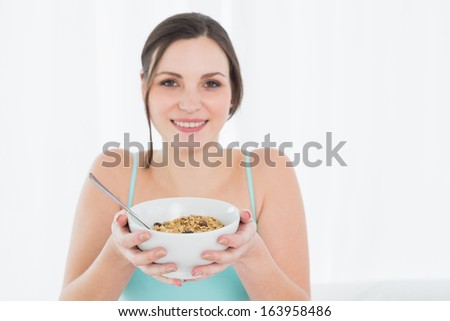 Close-up portrait of a young female with a bowl of cereal against white background