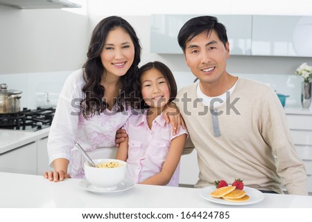 Portrait of a smiling couple with a daughter having breakfast in the kitchen at home