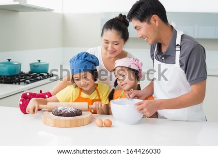 Happy family of four preparing cookies in the kitchen at home