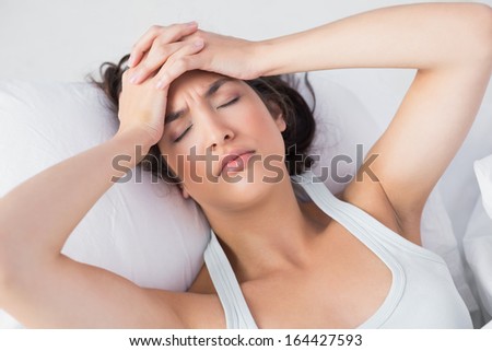 High Angle View Of A Sleepy Young Woman Suffering From Headache With Eyes Closed In Bed At Home