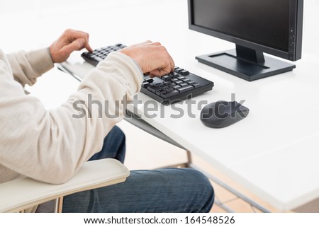 Side view mid section of a man using computer keyboard at the desk