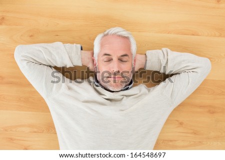 Overhead view of a mature man sleeping on parquet floor at home