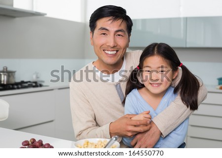 Portrait of a happy father with young daughter in the kitchen at home