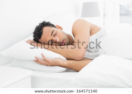 Side view of a young man sleeping in bed at home