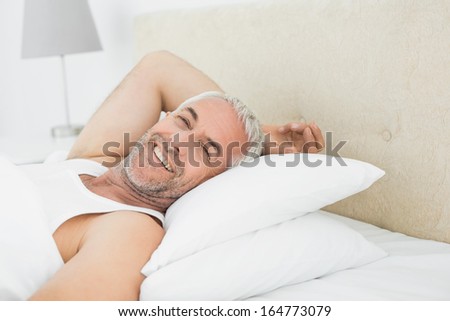 Close-up portrait of a smiling mature man resting in bed at home