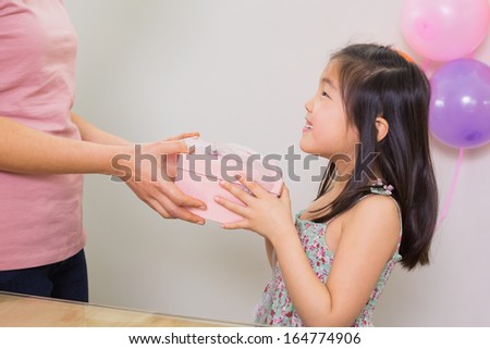 Close-up side view of a woman giving gift box to a little girl at a birthday party