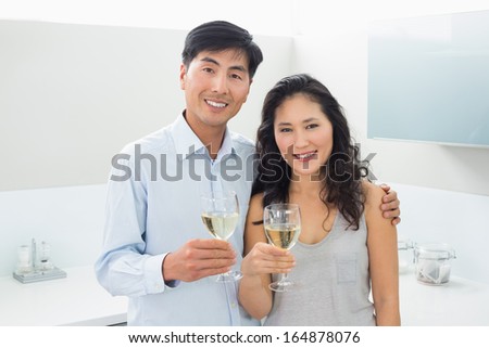 Portrait of a loving young couple with wine glasses in the kitchen at home