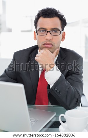Portrait of a serious elegant businessman in front of laptop at office desk