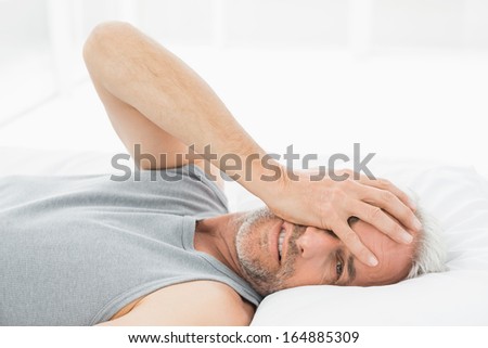 Portrait of a smiling mature man resting in bed at home