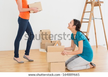 Two friends moving together in a new house and unwrapping boxes