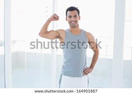 Portrait of a fit young man flexing muscles in a bright fitness studio
