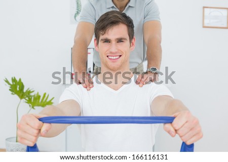 Portrait of a young man doing exercises with the help of therapist in the medical office
