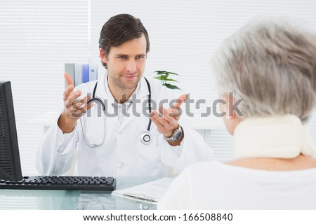 Smiling male doctor listening to senior patient with concentration at the medical office
