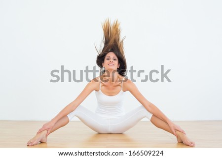 Full length portrait of a toned young woman tossing hair in fitness studio