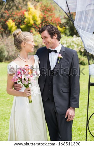 Attractive newlyweds smiling at each other in the countryside
