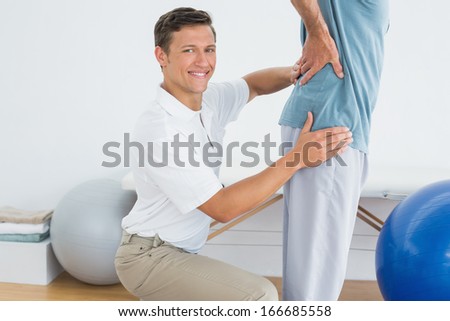 Side view portrait of a male therapist massaging mans lower back in the gym at hospital