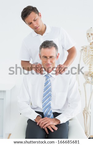 Male chiropractor massaging patients neck in the hospital